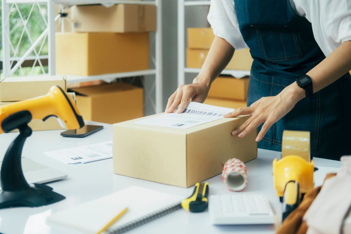 Warehouse worker applying a barcode label to a shipping box for order fulfillment, ensuring fast and accurate logistics processing.